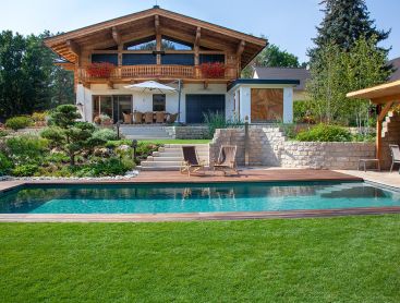 Natuurlijk zwembad met houten randen in de tuin voor een landelijk huis
